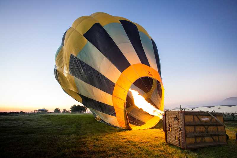 A yellow and blue hot air balloon getting ready for a flight at daytime